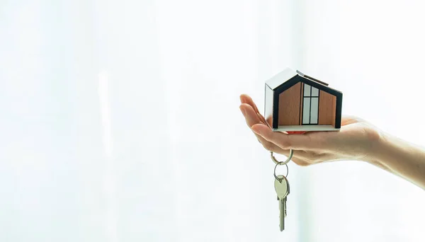 Architecture,construction,real estate,building and property concept. close up of hands holding home model and key on white background.Real estate agent holding house model and key on white background.