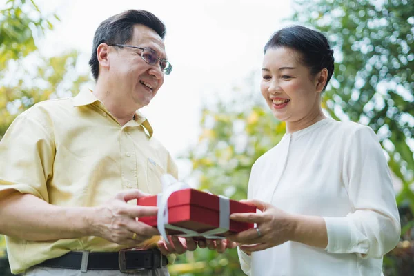 Hombre Asiático Senior Mostrando Caja Regalo Roja Con Cinta Blanca — Foto de Stock