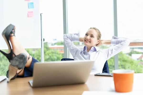 stock image Portrait of a relaxed young businesswoman sitting with legs on desk in a bright office.Happy business colleagues in modern office using labtop.