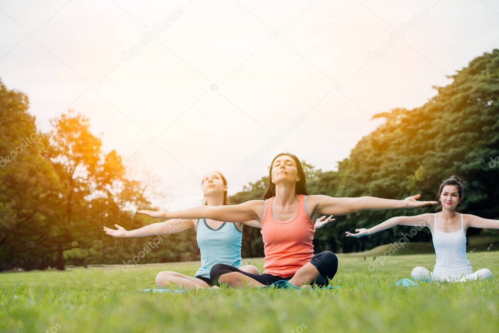 Yoga woman on green grass.group of adults attending a yoga class outside in park.Family or Friends enjoying relaxing yoga.
