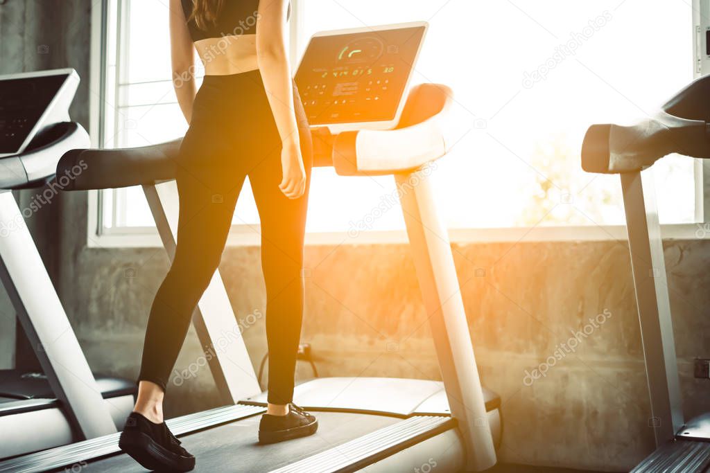 Female muscular feet in sneakers running on the treadmill at the gym. Concept for fitness, exercising and healthy lifestyle.sport concept. Young sporty woman stretching at gym. Change for health concept.Fitness woman in training showing exercises wit