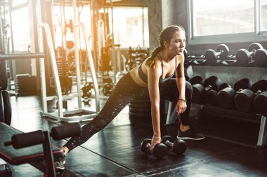 Spor salonunda spor yapmak için haltercilik oynayan genç bir kız, spor salonunda ağır halterleri kaldırıyor. Spor konsepti yağ yakma ve sağlıklı bir yaşam tarzı.