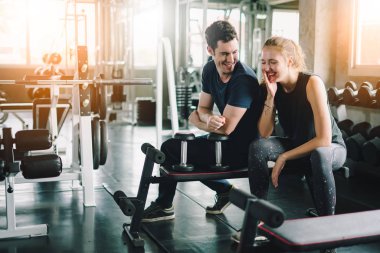 Spor, spor, spor, spor, takım çalışması, halter ve insan konseptinde halter kasları olan genç bir adam ve kişisel antrenör. Fitness kızı sabah dambılı kaldırıyor. Sağlık konsepti değişikliği.