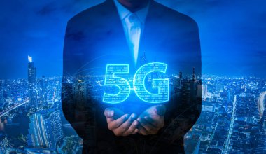 Şehir arka planında 5G ağ dijital hologramı tutan bir işadamı..