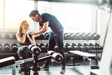 Spor, spor, spor, spor, takım çalışması, halter ve insan konseptinde halter kasları olan genç bir adam ve kişisel antrenör. Fitness kızı sabah dambılı kaldırıyor. Sağlık konsepti değişikliği.