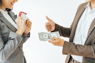 Real estate broker and customer shaking hands and pay after signing a contract: real estate, home loan and insurance concept.
