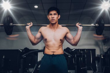 Muscular man working out in gym with barbell, strong Asian handsome male.