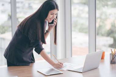 Ofiste cep telefonuyla konuşan kadın.
