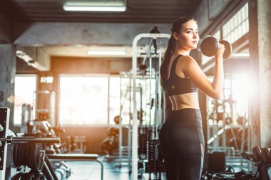 Spor salonunda spor yapmak için haltercilik oynayan genç bir kız, spor salonunda ağır halterleri kaldırıyor. Spor konsepti yağ yakma ve sağlıklı bir yaşam tarzı.