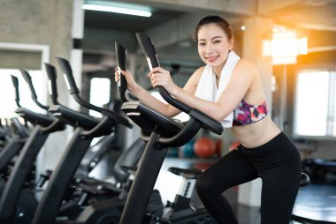 Young Asian girl exercising on bicycle in fitness center.
