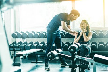 Spor, spor, spor, spor, takım çalışması, halter ve insan konseptinde halter kasları olan genç bir adam ve kişisel antrenör. Fitness kızı sabah dambılı kaldırıyor. Sağlık konsepti değişikliği.