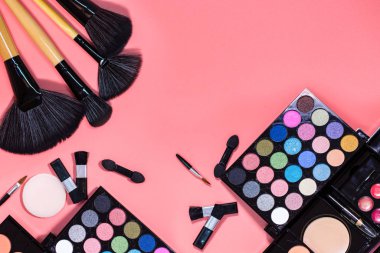 Güzellik dairesi kozmetikle kaplıydı. Makyaj ürünleri kozmetik poşetlerle ve pembe arka planda badem kurabiyeleri. Boşluğu kopyala..