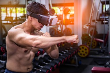Young fit boxer in vr glasses training in boxing game in virtual reality, futuristic gaming.