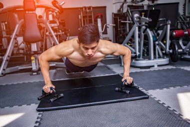 Attractive handsome muscular man training in modern gym.