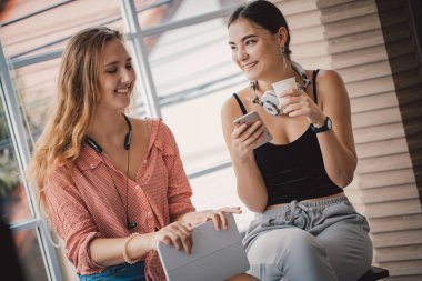 Tablet ve telefonla oynayan güzel beyaz kadınlar. rahatlama konsepti.