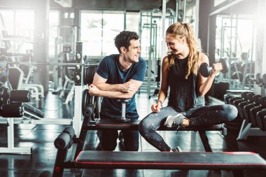 Spor, spor, spor, spor, takım çalışması, halter ve insan konseptinde halter kasları olan genç bir adam ve kişisel antrenör. Fitness kızı sabah dambılı kaldırıyor. Sağlık konsepti değişikliği.