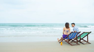 Mutlu balayı çifti Tayland sahilinde romantik bir yolculuk yaparken sandalyede oturuyor..