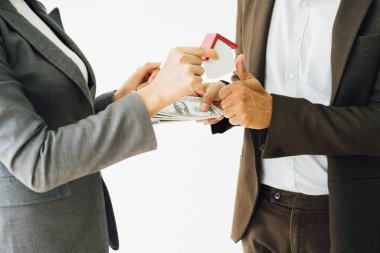 Real estate broker and customer shaking hands and pay after signing a contract: real estate, home loan and insurance concept.