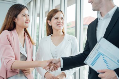 Patronla başarılı bir iş görüşmesi ve çalışanların el sıkışması. Genç bir kadın iş görüşmesine geliyor. Genç iş kadını bir işadamıyla tokalaşacak. Selamlaşma, anlaşma, birleşme ve satın alma kavramları..