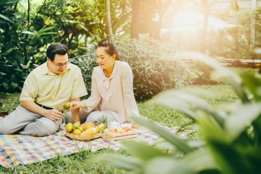 Parkta sonbaharda yaşlı ve güzel bir Asyalı çift. Parkta oturmuş çay ya da kahve içen yaşlı bir çiftin portresi..
