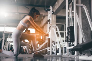 Young Asian fitness woman working out with exercise-machine in gym.