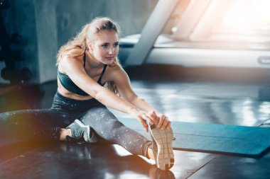 Spor salonunda sağ bacağını esneten esnek genç bir kadın. Spor salonunda esneyen esnek bir kadın..