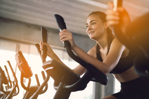 Young People - group of women and men - doing sport biking in the gym for fitness. Young woman workout in gym healthy lifestyle. Change for health concept.