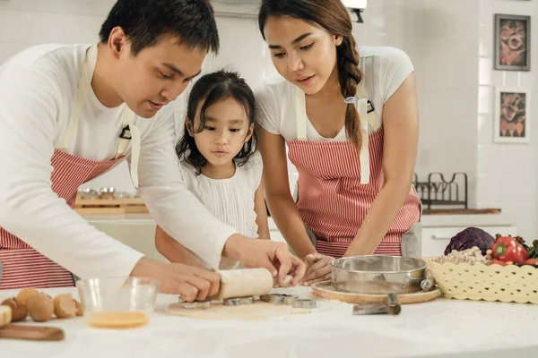 Young asian family cooking food in kitchen.Happy Little girl with her father and mother mixing batter.mother and Little girl preparing the dough.Happy family in the kitchen and junior chef Concept.