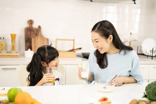 Healthy food at home and Happy family in the kitchen concept. Mother and child daughter are having breakfast.Cute little girl and her beautiful parents are making breakfast while cooking in kitchen.