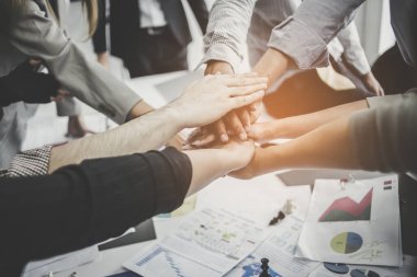 İş adamları toplantı sırasında el ele tutuşurlar. Başarı ve kazanma konsepti - ofiste zaferi kutlayan mutlu iş takımı.