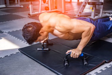 Attractive athletic muscular man training in modern gym.