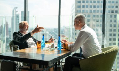 Toplantı ve tartışma kavramı. Ofiste iletişim kuran iş adamları. Olgun iş adamı, bir ofis kulesinde, modern bir iş yerindeki bir meslektaşıyla bilgi tartışır..