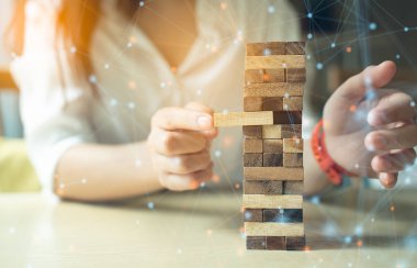 İş organizasyonu stratejisi başlangıç konsepti. İş kadını ahşap masa üzerine tahta blok inşa etmeye çalışıyor..