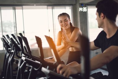 Gençler - bir grup kadın ve erkek - spor salonunda spor bisikleti yapıyorlar. Genç kadın spor salonunda sağlıklı bir yaşam tarzında çalışıyor. Sağlık konsepti değişikliği.