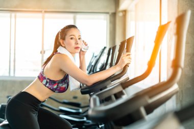 Gym woman working out and wiping face with towel, hardworking female.