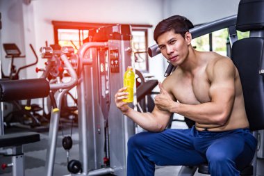 Asian fit man with energy drink relaxing in gym, sport and fitness concept.