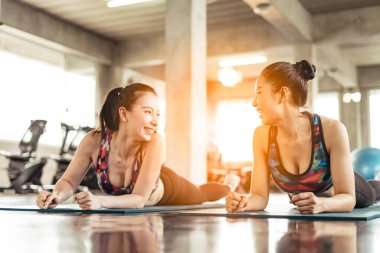 Beautiful Asian women talking while working out in gym together.