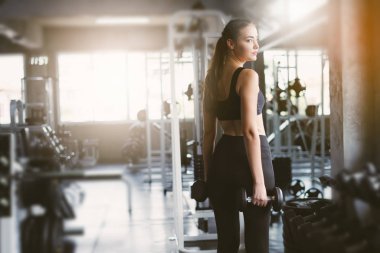 Spor salonunda spor yapmak için haltercilik oynayan genç bir kız, spor salonunda ağır halterleri kaldırıyor. Spor konsepti yağ yakma ve sağlıklı bir yaşam tarzı.