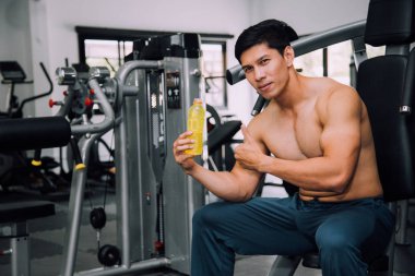 Asian fit man with energy drink relaxing in gym, sport and fitness concept.