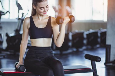 Spor salonunda spor yapmak için haltercilik oynayan genç bir kız, spor salonunda ağır halterleri kaldırıyor. Spor konsepti yağ yakma ve sağlıklı bir yaşam tarzı.