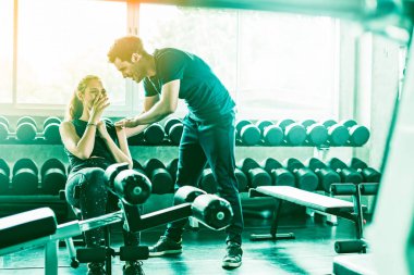 Spor, spor, spor, spor, takım çalışması, halter ve insan konseptinde halter kasları olan genç bir adam ve kişisel antrenör. Fitness kızı sabah dambılı kaldırıyor. Sağlık konsepti değişikliği.