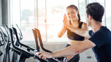 Gençler - bir grup kadın ve erkek - spor salonunda spor bisikleti yapıyorlar. Genç kadın spor salonunda sağlıklı bir yaşam tarzında çalışıyor. Sağlık konsepti değişikliği.