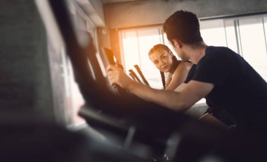 Gençler - bir grup kadın ve erkek - spor salonunda spor bisikleti yapıyorlar. Genç kadın spor salonunda sağlıklı bir yaşam tarzında çalışıyor. Sağlık konsepti değişikliği.