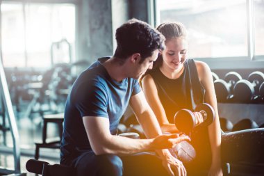 Spor, spor, spor, spor, takım çalışması, halter ve insan konseptinde halter kasları olan genç bir adam ve kişisel antrenör. Fitness kızı sabah dambılı kaldırıyor. Sağlık konsepti değişikliği.