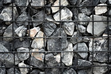 Tel örgülü taşlar. Bahçe düzenlemesi için popüler bir tasarım unsuru. Taş ve çeliğin arka planı..