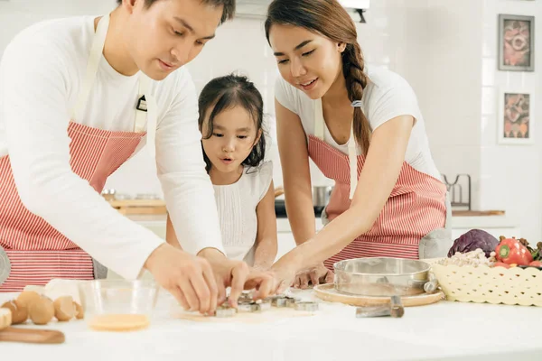 Young asian family cooking food in kitchen.Happy Little girl with her father and mother mixing batter.mother and Little girl preparing the dough.Happy family in the kitchen and junior chef Concept.