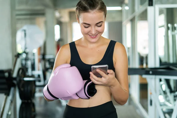 woman using mobile phone and listen music at gym.Healthy concept, Beautiful sports girl relax after workout in gym.