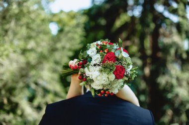 onun arkasından elinde düğün buketi