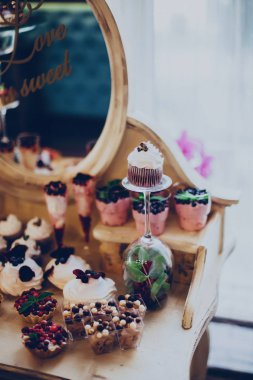 Düğün tatlılar kapaklar ve kek bir ayna restoranda bir altın renkli arka plan üzerinde