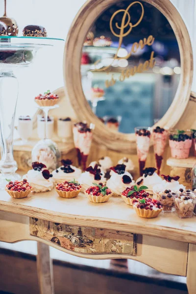 Dolci nuziali di berretti e torte sullo sfondo di uno specchio in un colore dorato al ristorante — Foto Stock